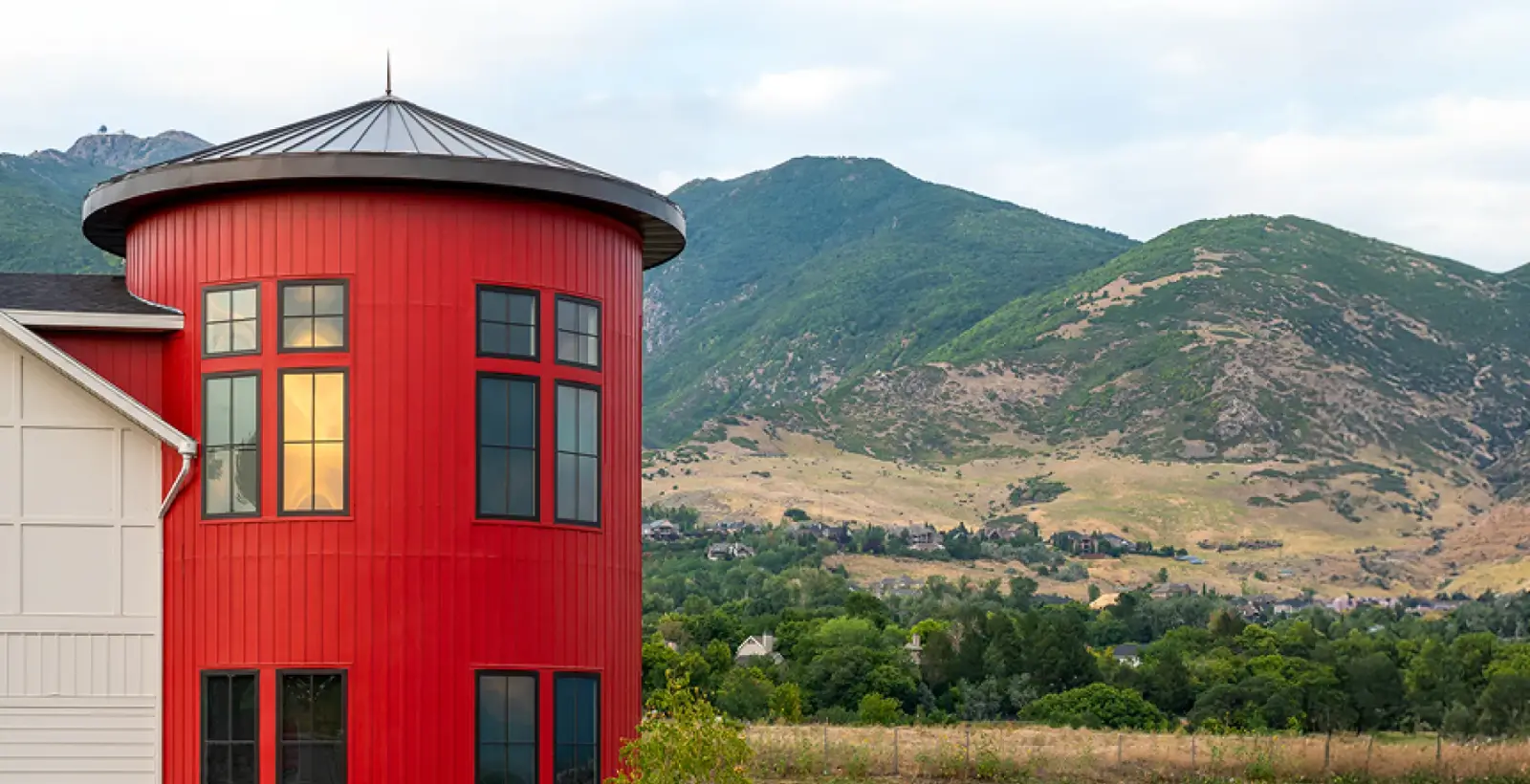 The red silo tower of Oakridge Dental's office against green Wasatch foothills